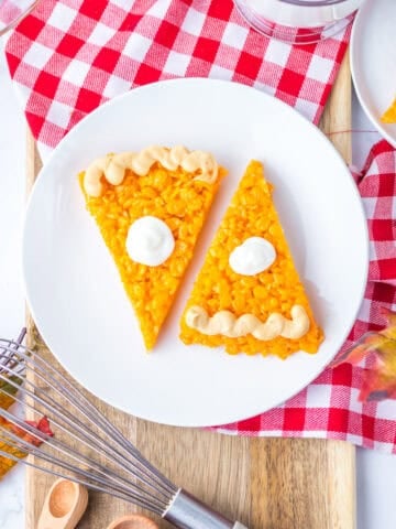 Overhead image of two pumpkin pie rice krispies on a plate in the center, with an additional slice on a smaller plate nearby.