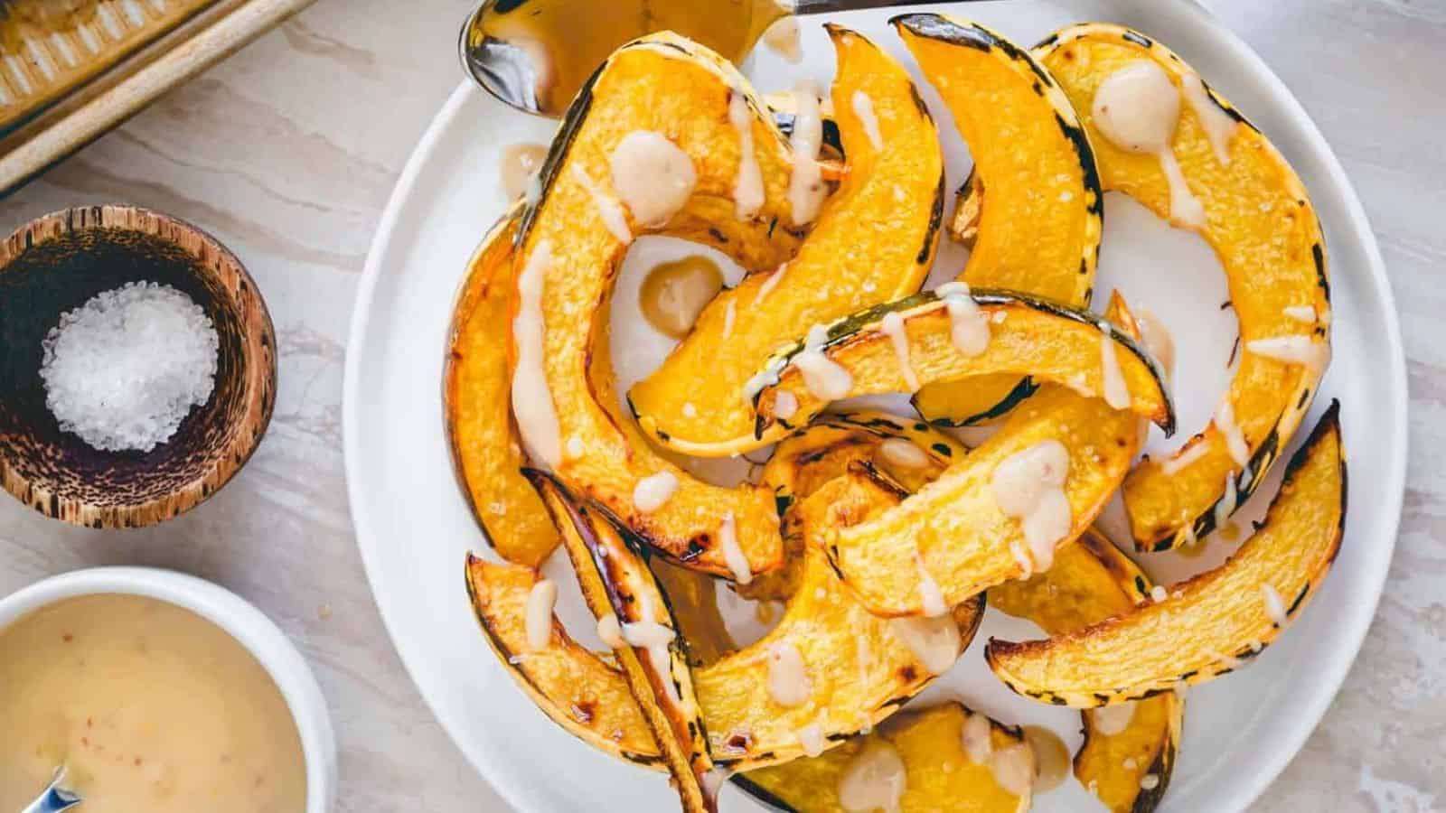 Overhead image of roasted sweet dumpling squash qith tahini maple dijon sauce on a plate.