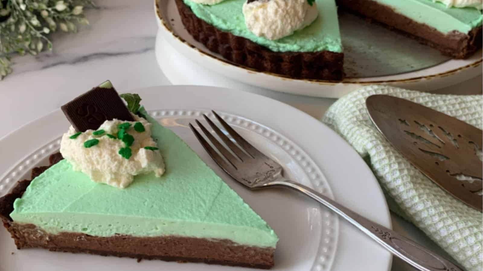 A slice of a chocolate tart with whipped cream on top on a white plate.