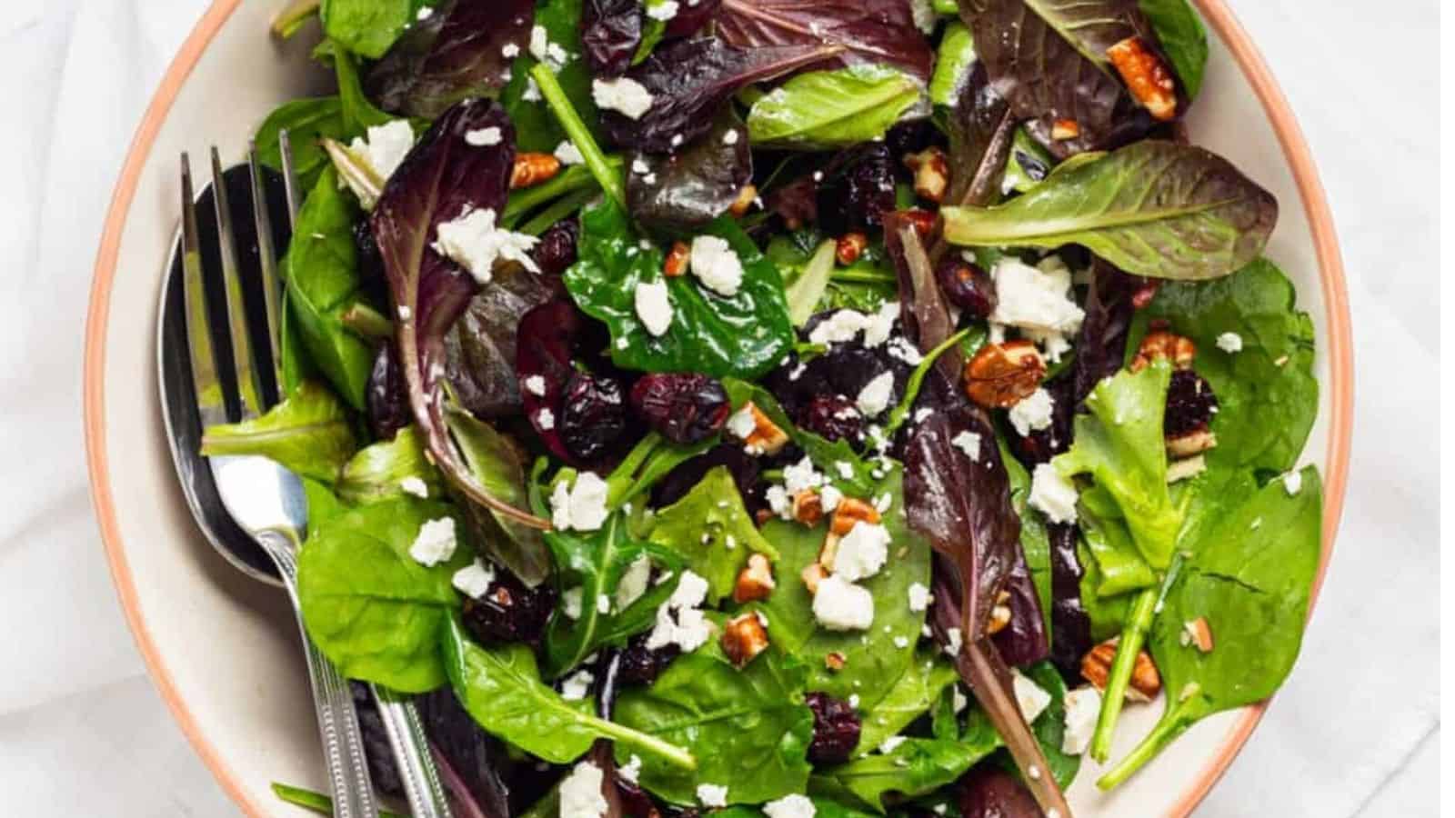 Close-up of an overhead image of cranberry salad with pecans served in a white salad bowl with a fork on the side.