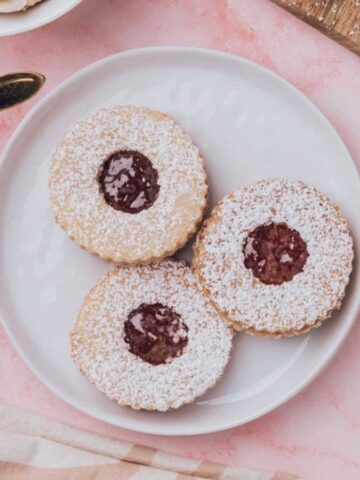 An overhead image of three Linzer cookies on a plate.