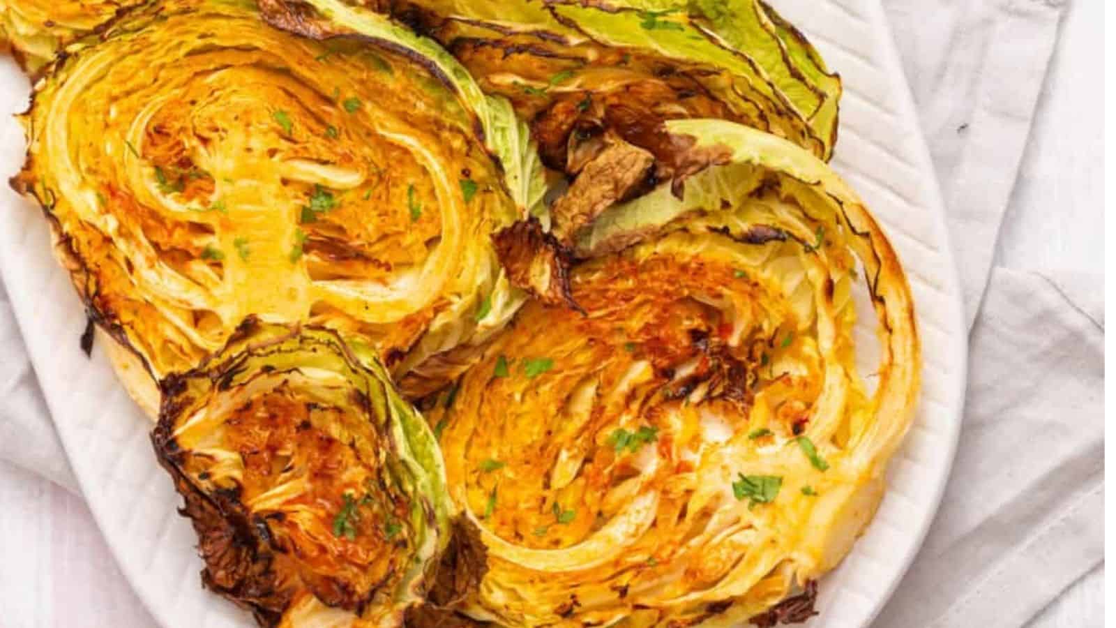 Close-up of an overhead image of roasted cabbage steaks on a serving plate.