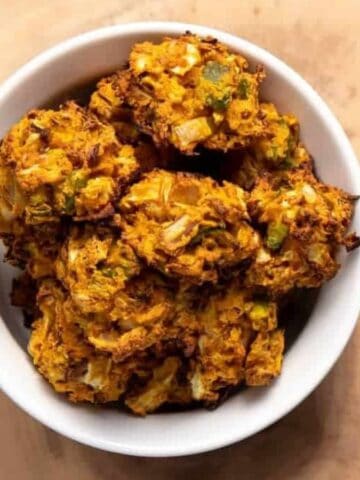 A bowl of vegan cabbage fritters on a wooden board.