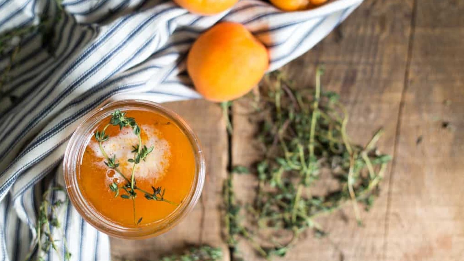 Overhead of apricot jam with apricots and thyme.