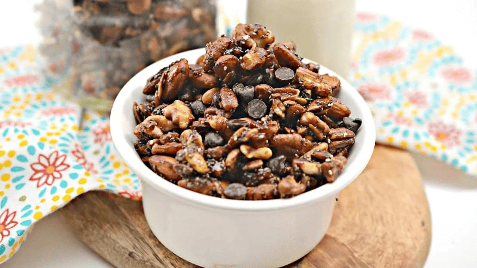 Chocolate pecan granola in a bowl next to a glass of milk.