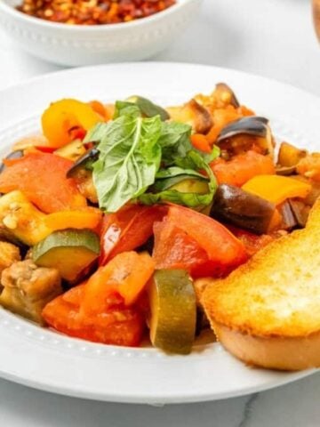 An image of ratatouille on a plate with bread.