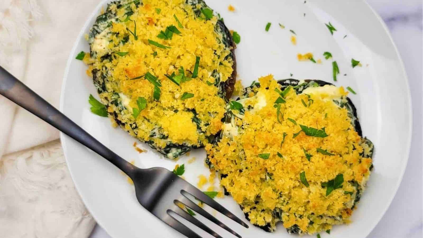 Two spinach-stuffed portobello mushrooms on a white plate.