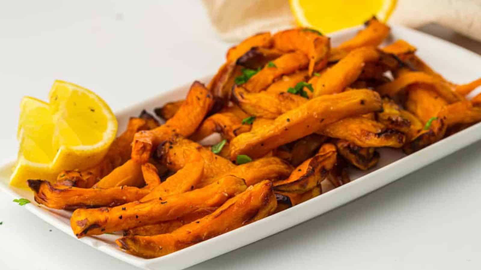 A plate of sweet potato fries with a wooden spoon.