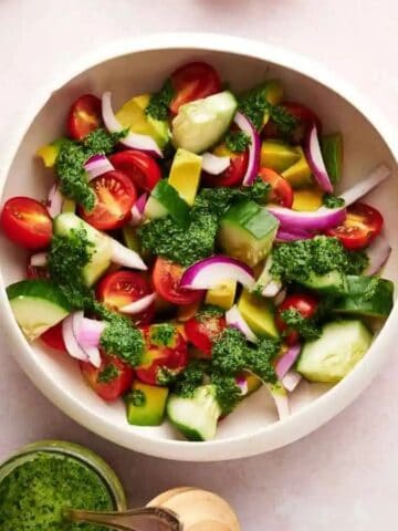 A bowl of Avocado Salad with a variety of ingredients around it.