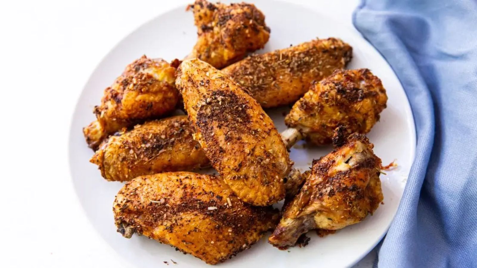 Easy Air Fryer Chicken Wings with Keto Dry Rub, parsley, and a white sauce.