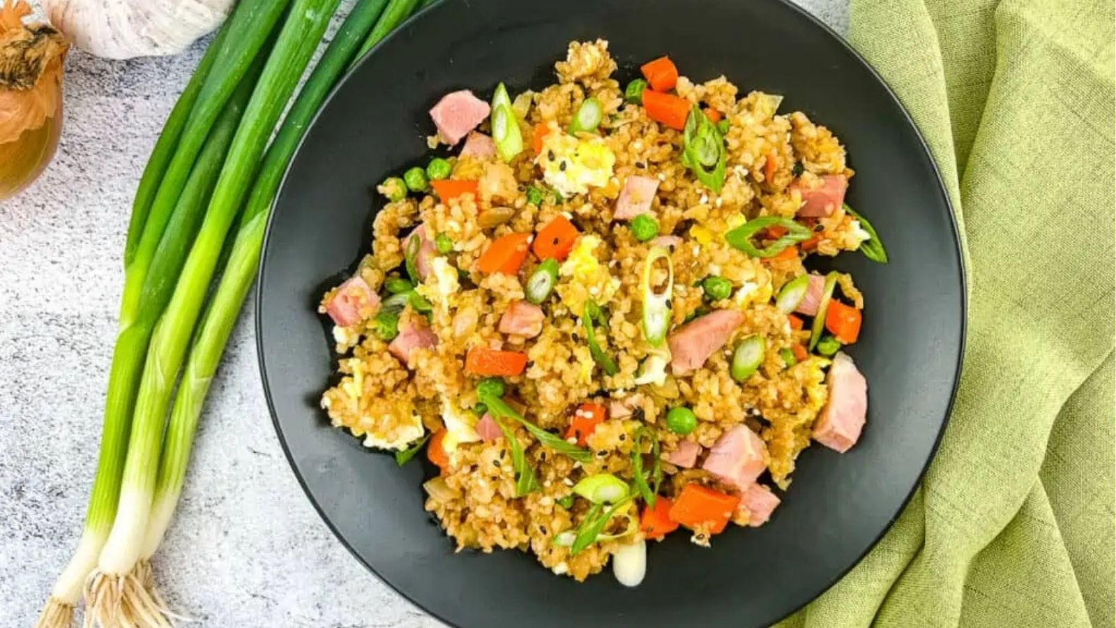 Overhead image of ham fried rice on a black plate.