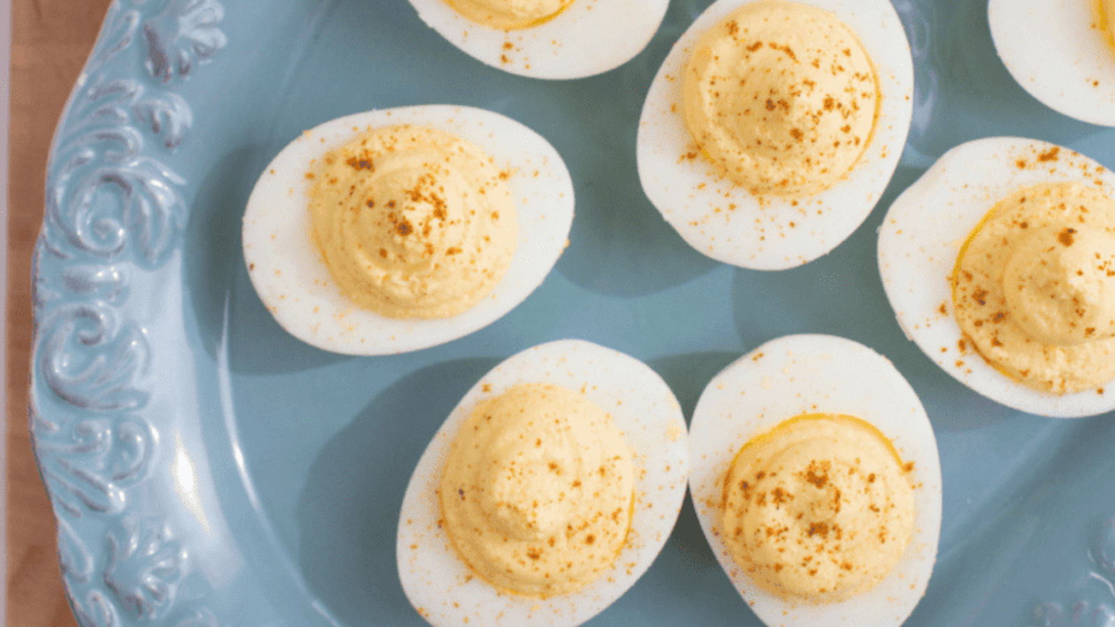 Deviled eggs topped with paprika on a blue plate.