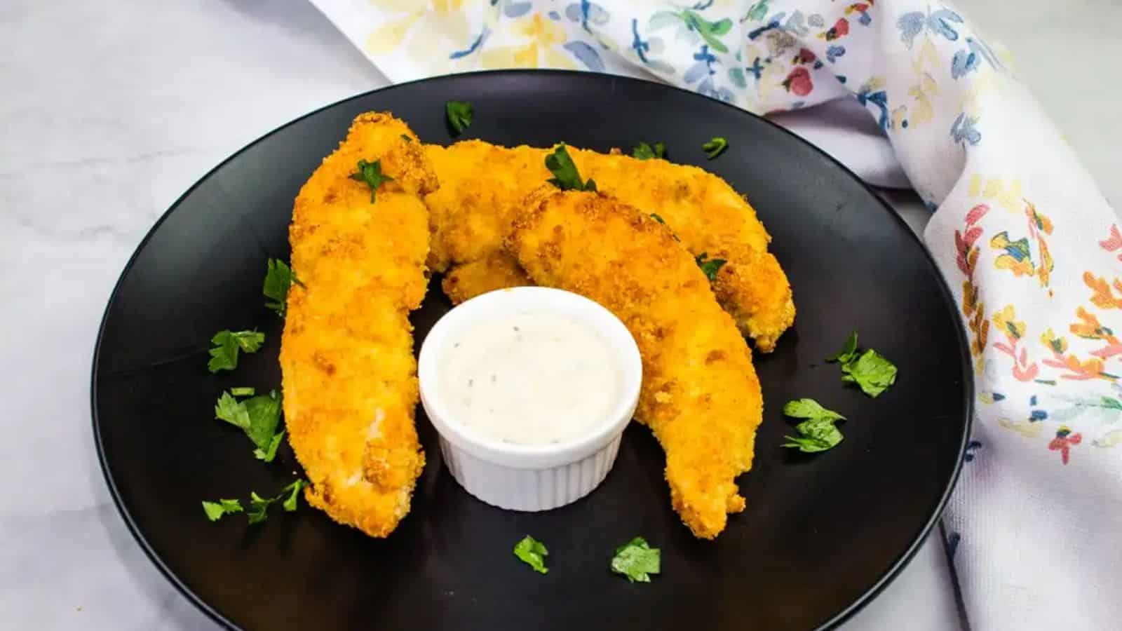 Keto Air Fryer Chicken Tenders and a dip on a black plate.