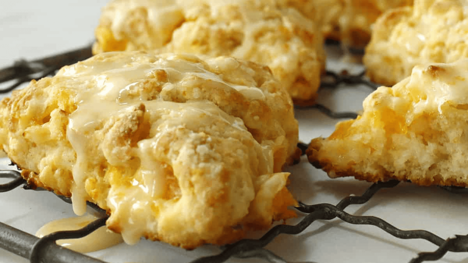 Orange scones on a wire rack with oranges in the background.