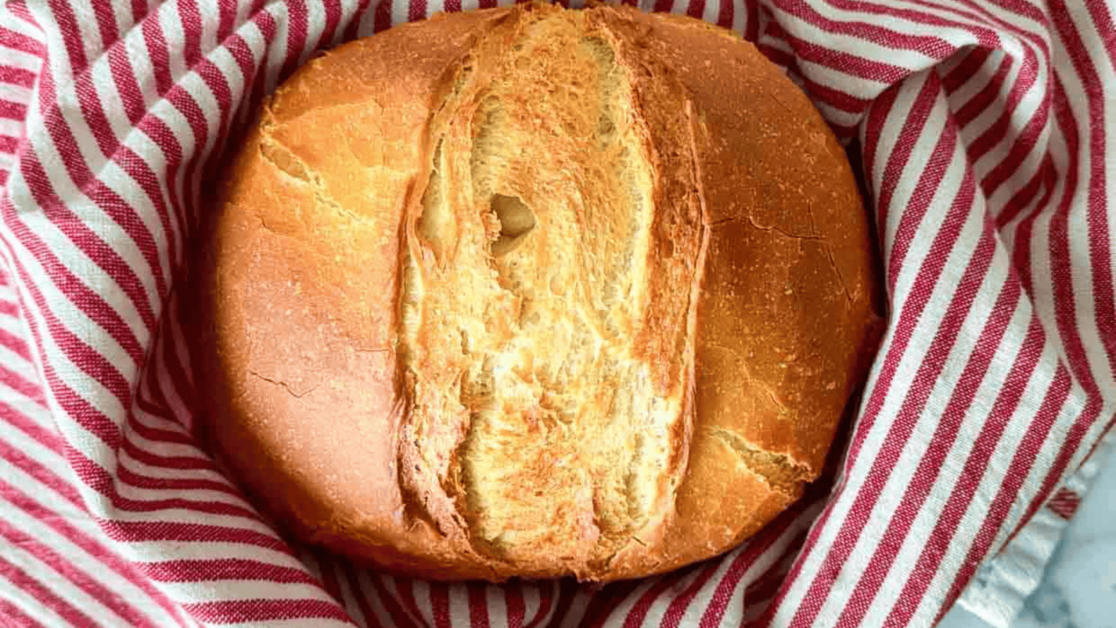 A loaf of bread in a red and white striped towel.