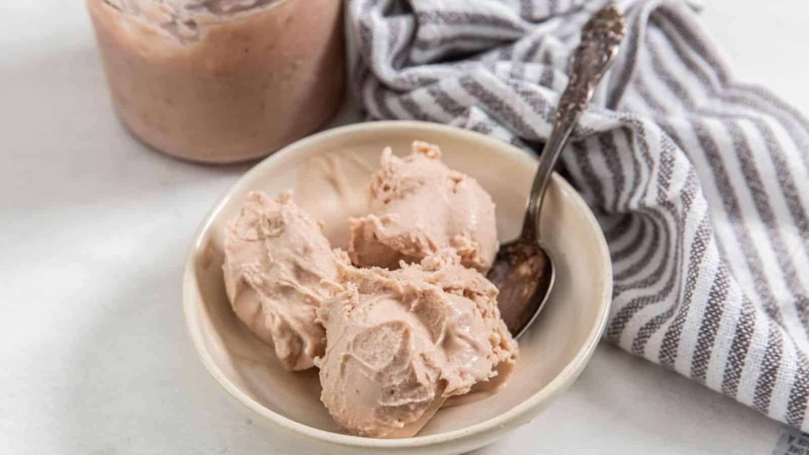 Three scoops of Strawberry and Banana Ice Cream in a bowl with a spoon.