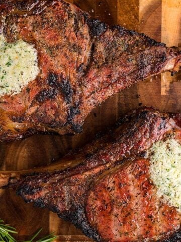 Two Smoked Tomahawk Steaks on a wooden board.