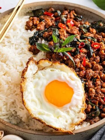 A bowl of rice topped with a fried egg and Thai Basil Pork – Pad Kra Pao.