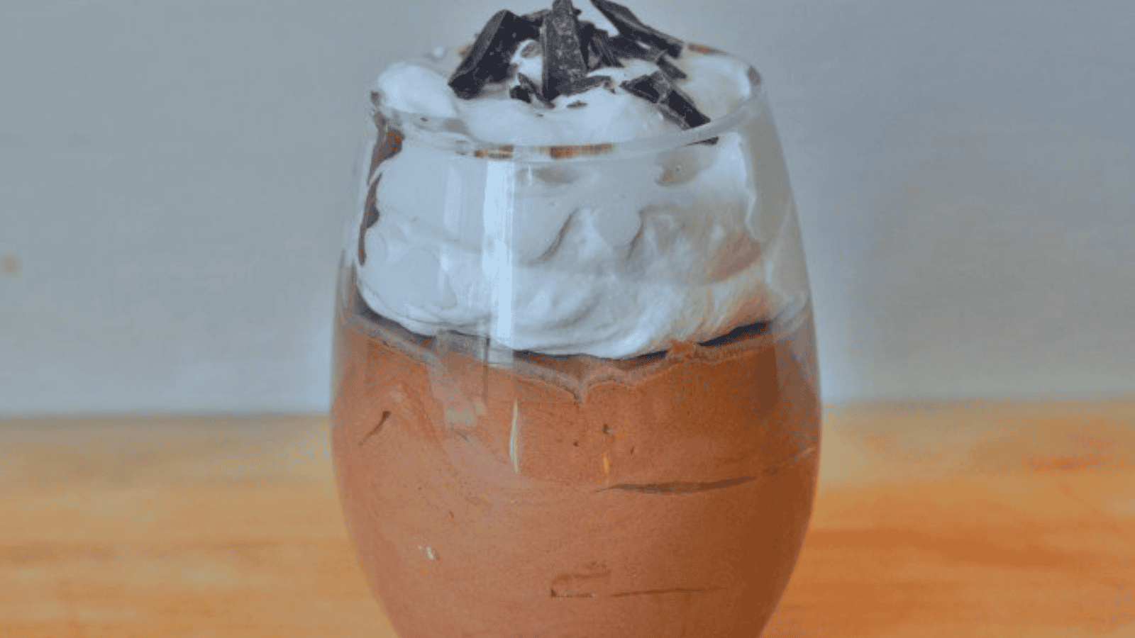 Image shows a Spoon with Baileys chocolate mousse and whipped cream and the full serving behind it.