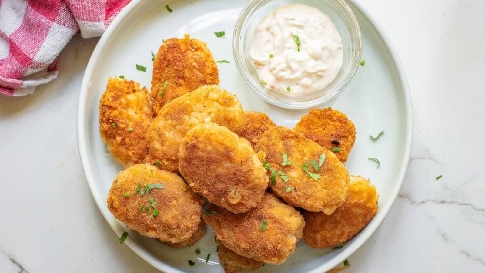 A close up image of cauliflower nuggets on a plate with sauce on the side.