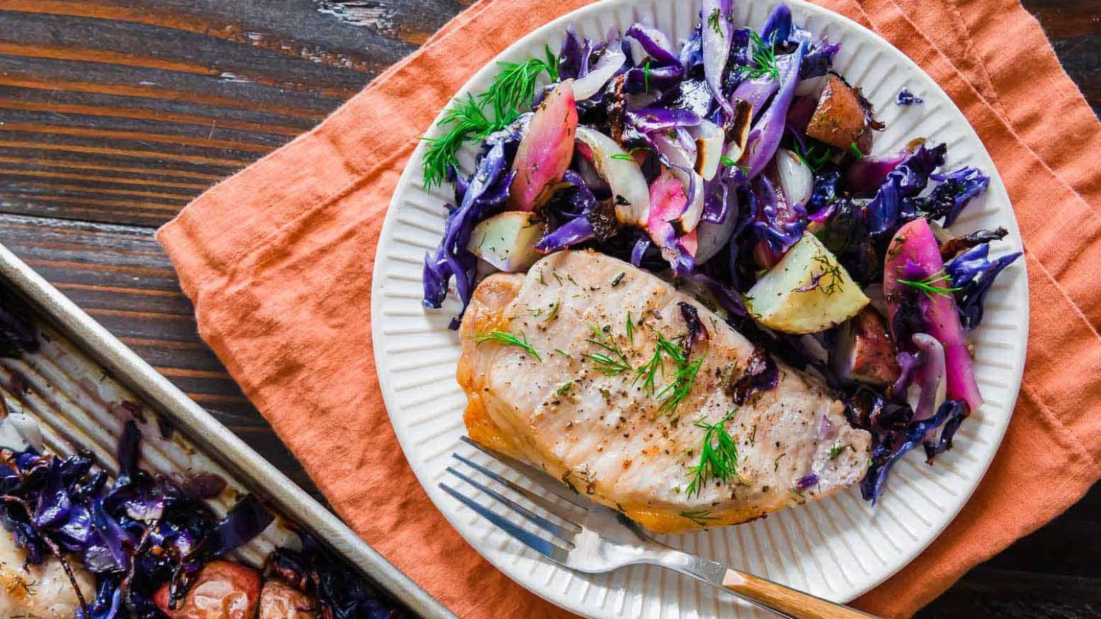 A plate of Sheet Pan Pork Chops with Cabbage, Apples, and Potatoes.