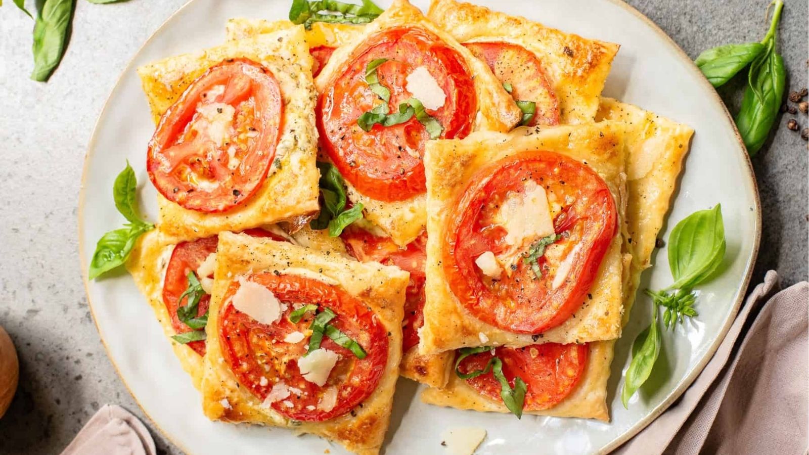 An overhead image of tomato puff pastry tarts on a serving plate.