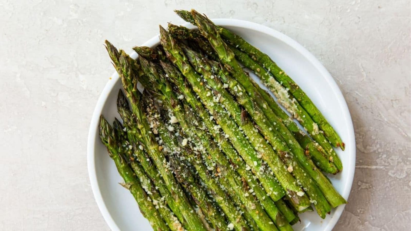 Air Fryer Parmesan Asparagus (Keto & Gluten Free) on a white plate with parmesan cheese.