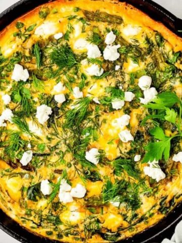 An overhead image of asparagus frittata in a cast iron skillet.