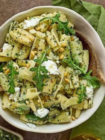 An overview of a bowl of Cavatelli with Arugula Pesto and two wooden spoons.