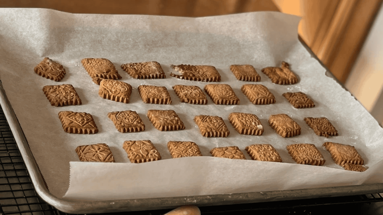 A man is using an embossed rolling pin to roll out dough on a table.