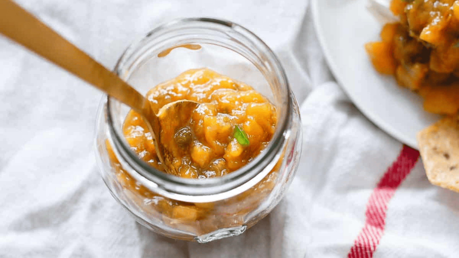 Jalapeño mango jam in a glass jar with a spoon.