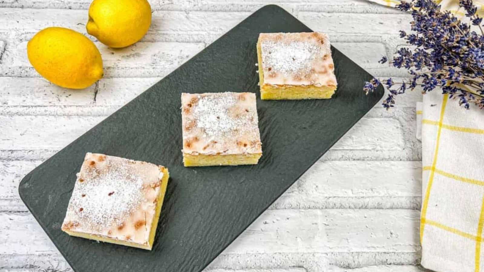 Three square pieces of lemon goldies on a white plate.