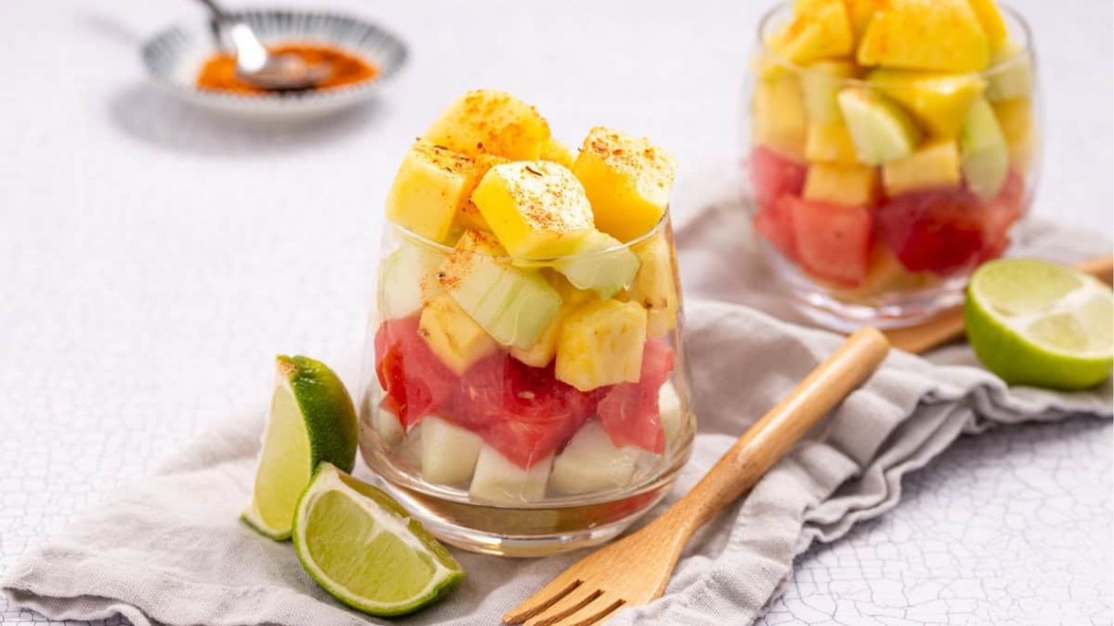 An image of Mexican fruit cup with sliced limes on the side.