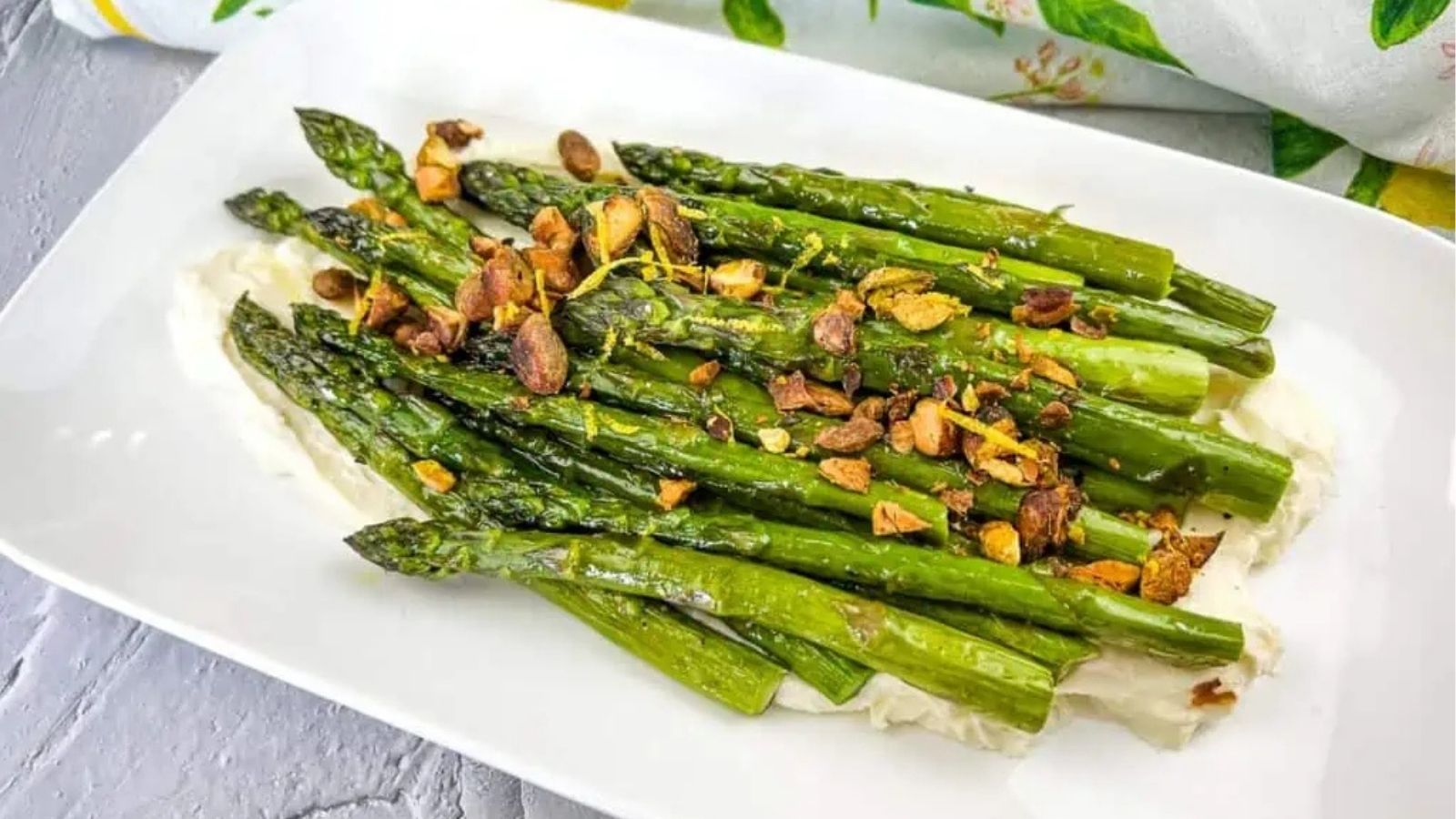 Close-up image of oven-roasted asparagus with mascarpone on a dish.