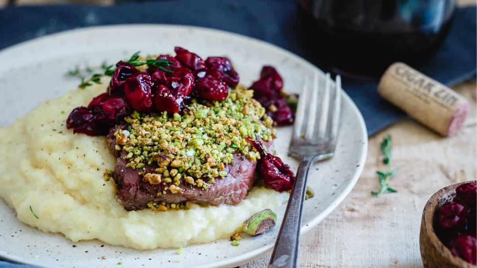 Close-up image of Pistachio crusted lamb chops with red wine cherries on a plate.