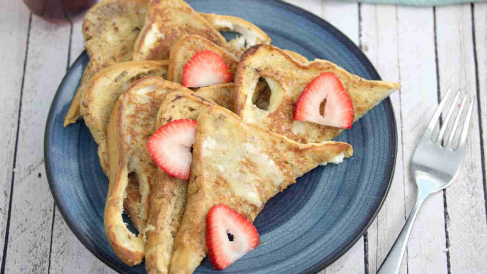 A blue plate with protein french toast in triangle slices with strawberries on it.