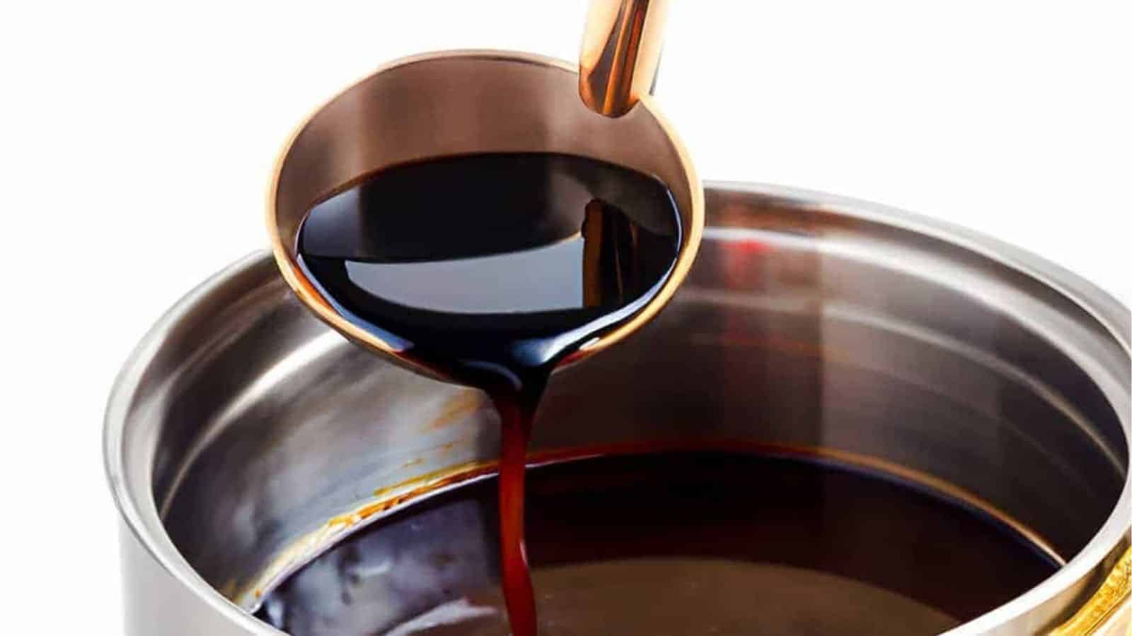 A ladle pouring red wine sauce into a saucepan.