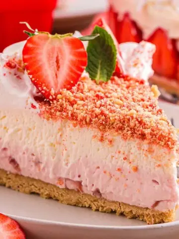 A slice of Strawberry Shortcake Cheesecake on a plate with a fork.