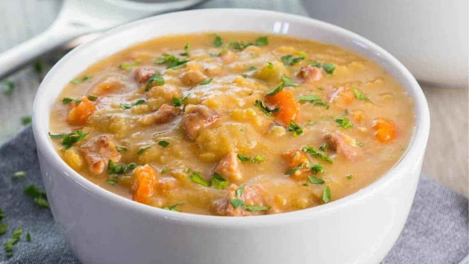 A bowl of soup, with Bacon and vegetables in it.