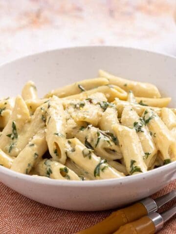 A picture of pasta with basil cream sauce in a bowl and forks.