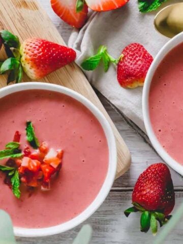 Top view of two bowls of Cold Strawberry Soup surrounded by fresh strawberries.