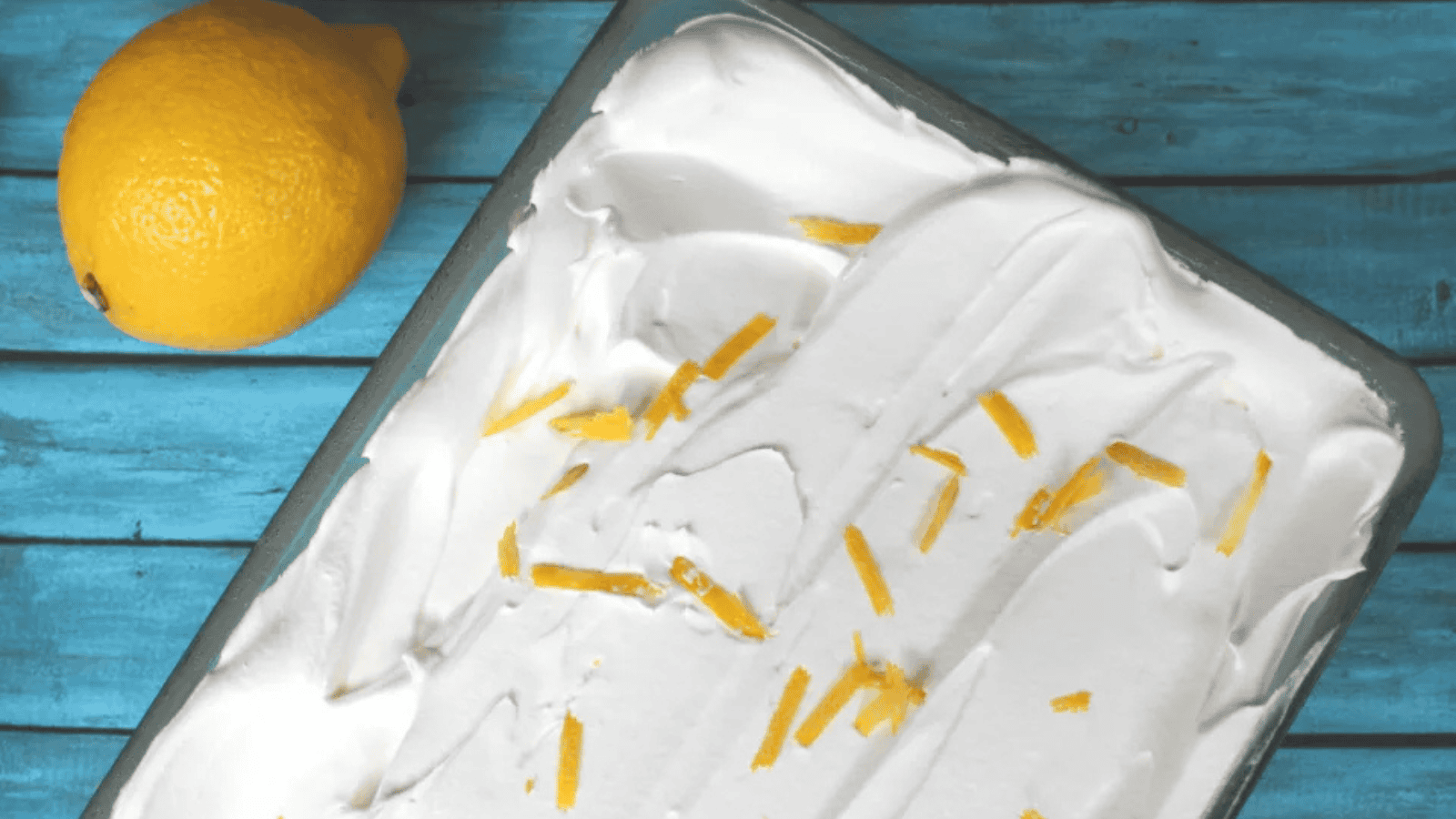 A piece of cake on a teal plate on a wooden background.