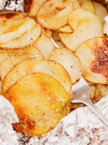 A close-up image of Grilled Foil Packet Adobo Potatoes with a fork.
