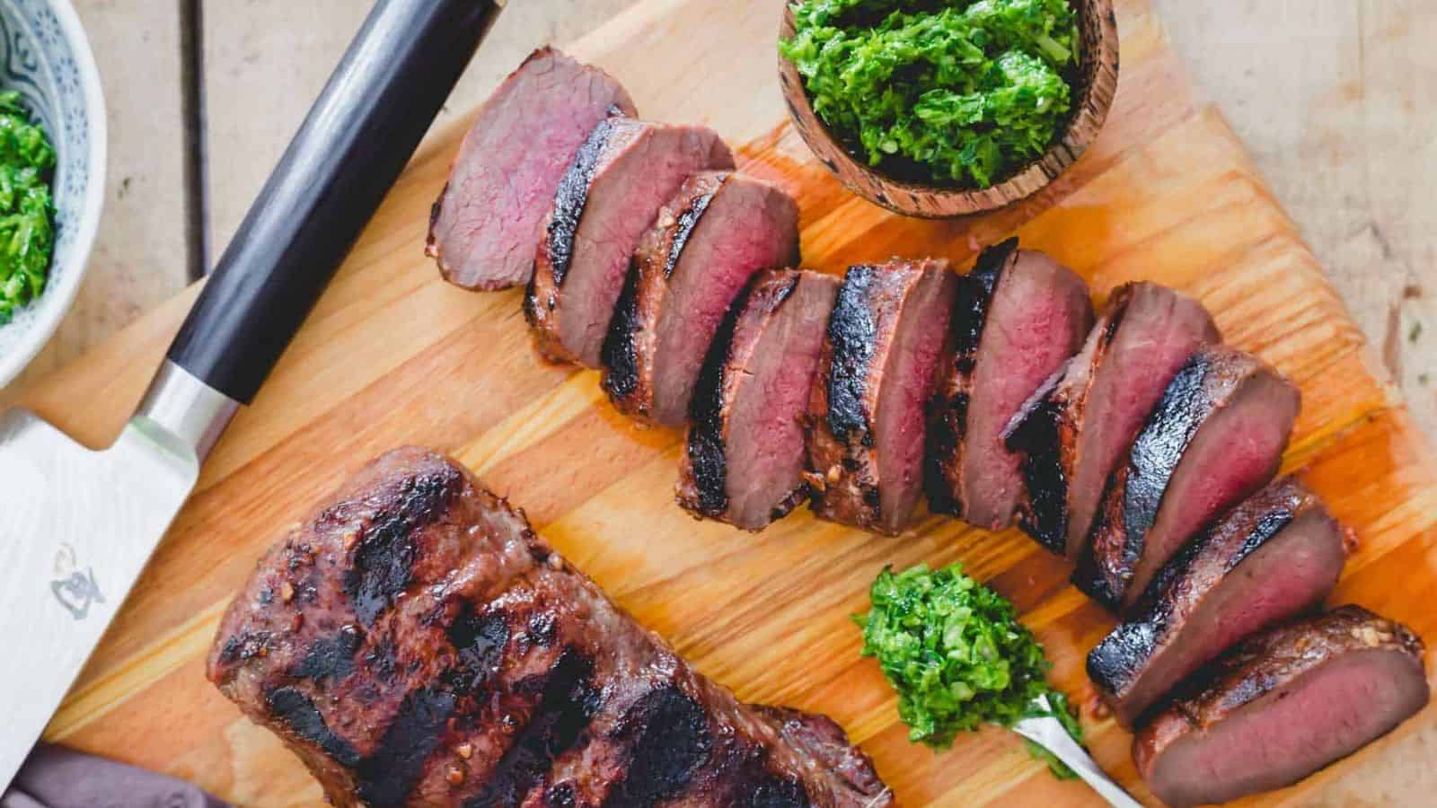Slices of Grilled Venison Backstrap on a wooden board.