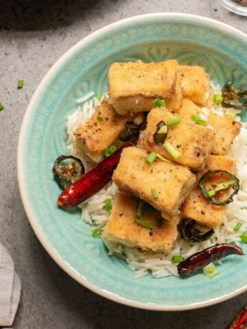An overhead image of salt and pepper tofu in a bowl with rice.