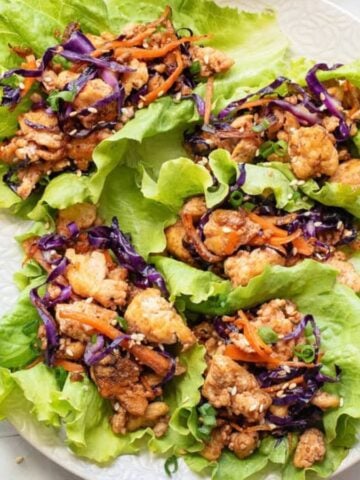 An overview of five tofu lettuce wraps on a white plate.