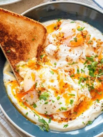 An overhead image of Cilbir, Turkish eggs, on a serving plate.