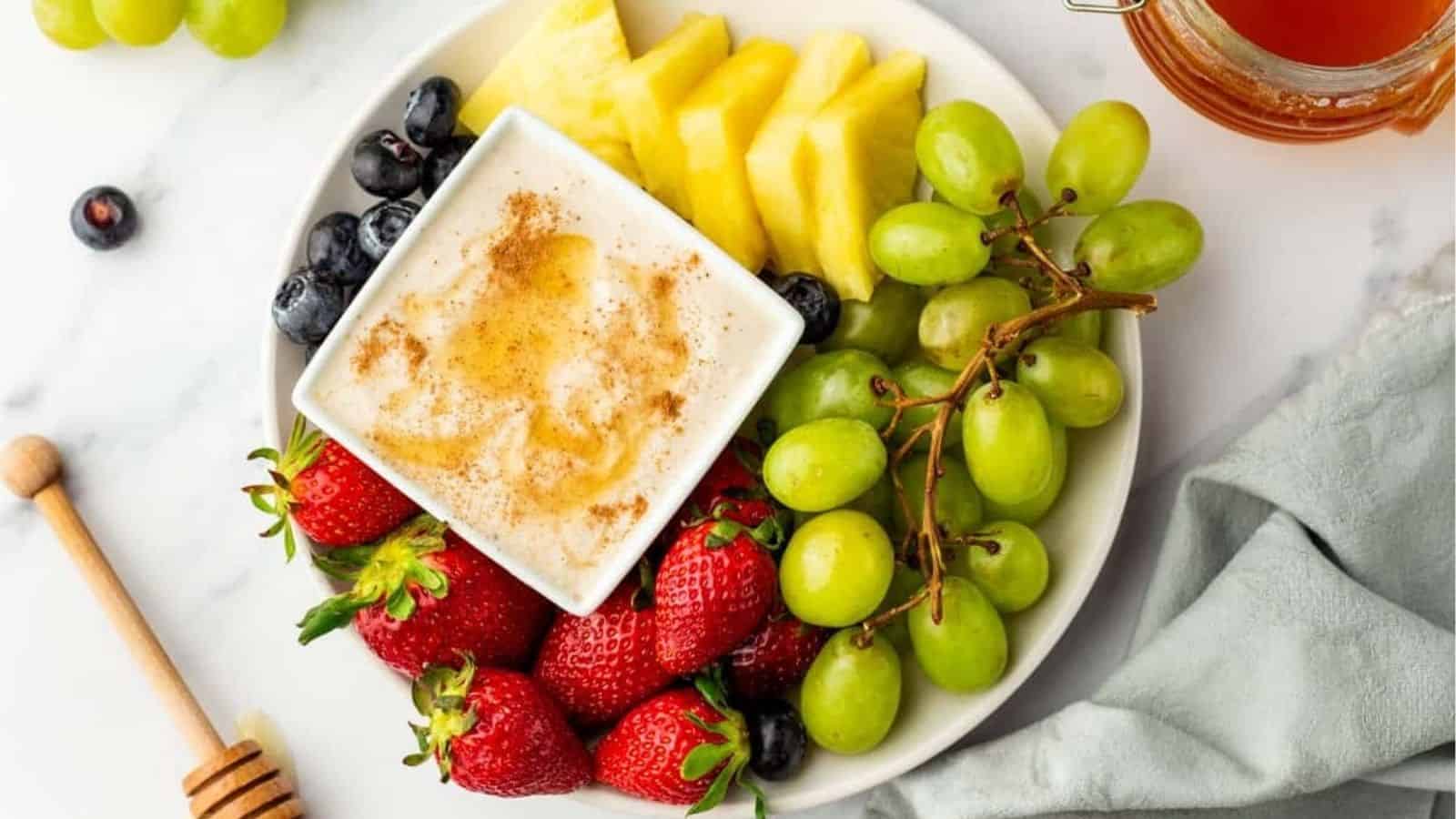 An overhead image of cottage cheese fruit dip on a platter with fruits on the side.