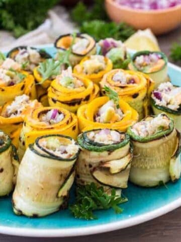 A blue plate full of Snow Crab Stuffed Zucchini Rolls.