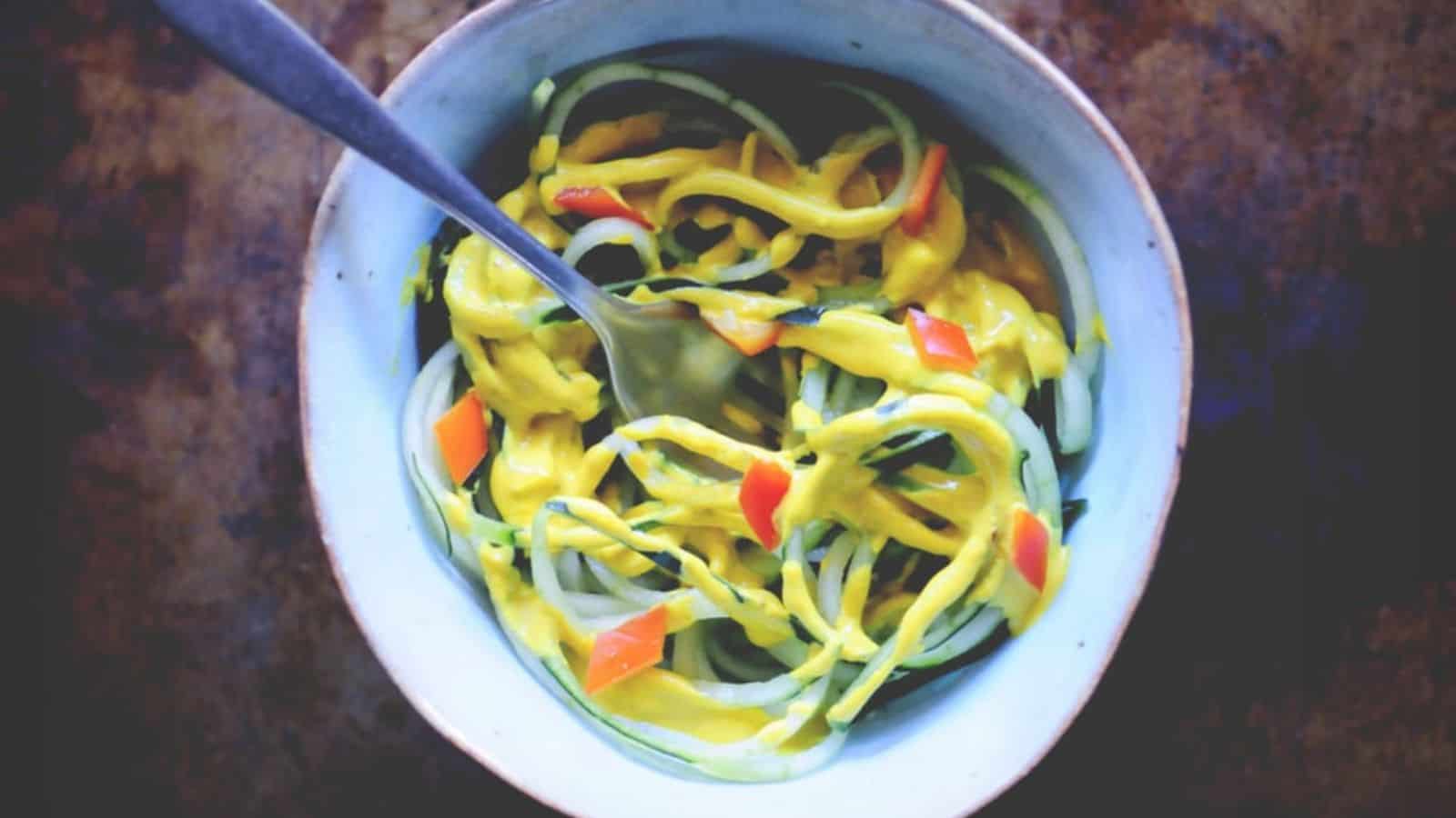 An overview of a bowl of Spicy Spiralized Turmeric Tahini Cucumber Noodles with a fork.